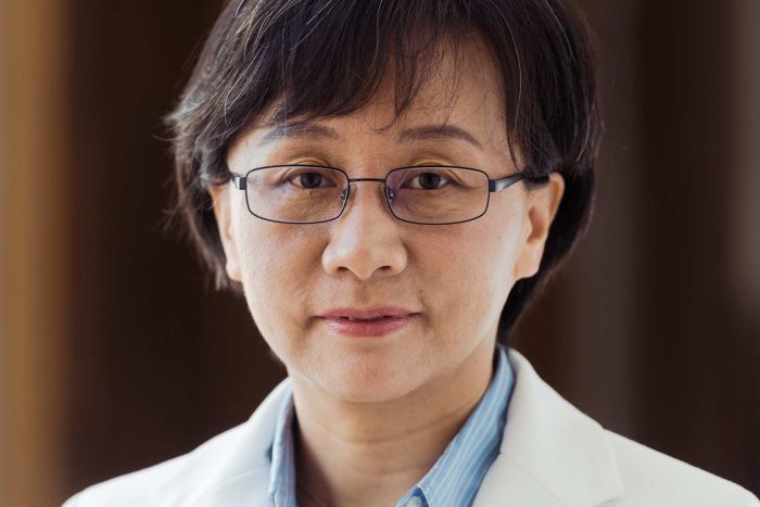 Dong Zhihua A headshot of a woman in a blue shirt and cream jacket.