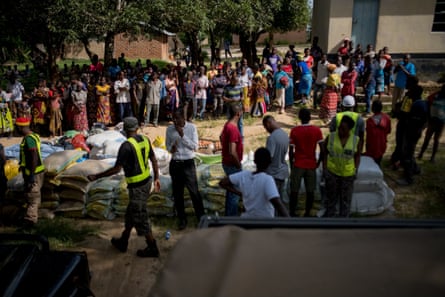 Officials with sacks of food stacked up as rural African women wait