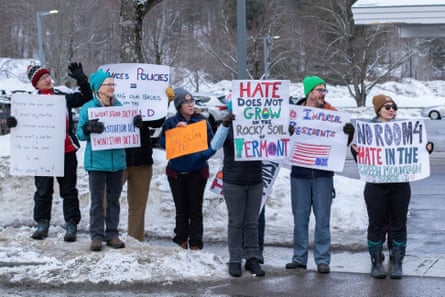 people hold signs against JD Vance