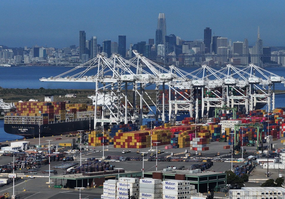 Aerial view of the Port of Oakland, showing cargo ships, cranes, and containers.