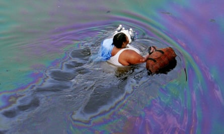 A New Orleans resident walks through floodwaters coated with a fine layer of oil in the flooded downtown area on Tuesday, Aug. 30, 2005.