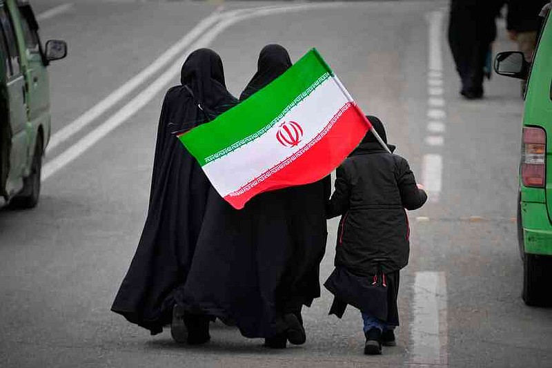 Two women and a child holding an Iranian flag walk toward the Imam Khomeini Grand Mosque to attend Friday prayers in Tehran, Iran, Friday, March 20, 2026. (AP Photo/Vahid Salemi)
