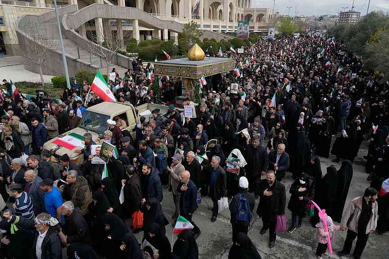 People follow a truck carrying the flag draped coffins of Gen. Ali Mohammad Naeini, a spokesperson for Iran's paramilitary Revolutionary Guard and one of his comrades Amir Hossein Bidi , during their funeral procession in Tehran, Iran, Saturday, March 21, 2026. (AP Photo/Vahid Salemi)
