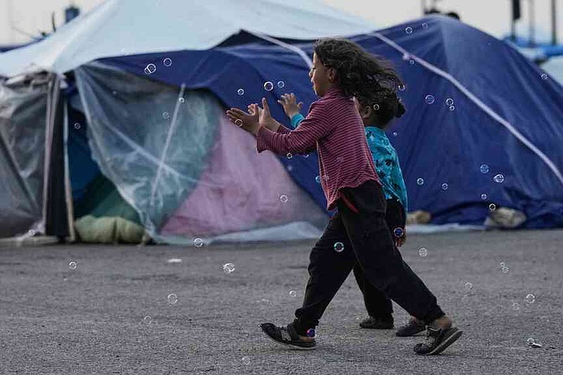 Girls chase bubbles next to their family's tents used as shelter after fleeing Israeli bombardment in Dahiyeh, Beirut's southern suburbs, in Beirut, on Wednesday, April 15, 2026. (AP Photo/Bilal Hussein)