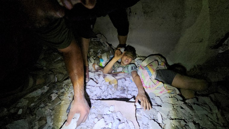 Palestinians work to rescue a boy trapped in the rubble following an Israeli strike on a house in Jabalia in the northern Gaza Strip, October 19, 2023.