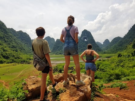 A woman and two children walking in Vietnam, mountains all around them