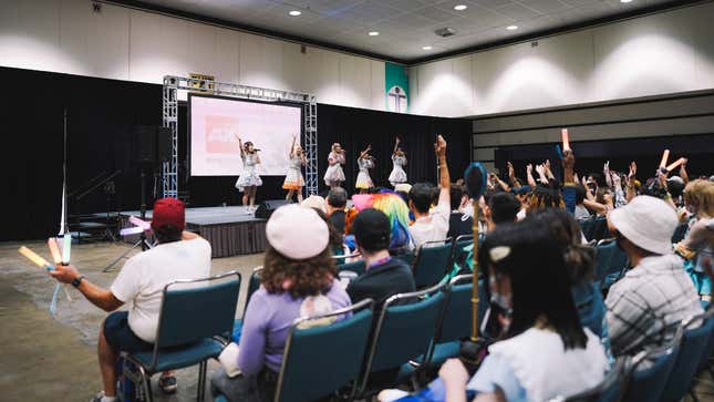 A photo shows idols dance on stage at Anime Expo.
