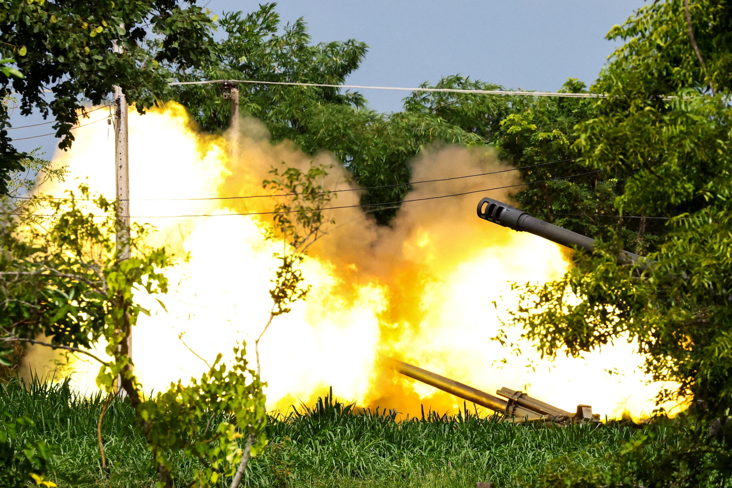 A Thai military mobile unit fires toward Cambodia's side, creating a large fireball and smoke.