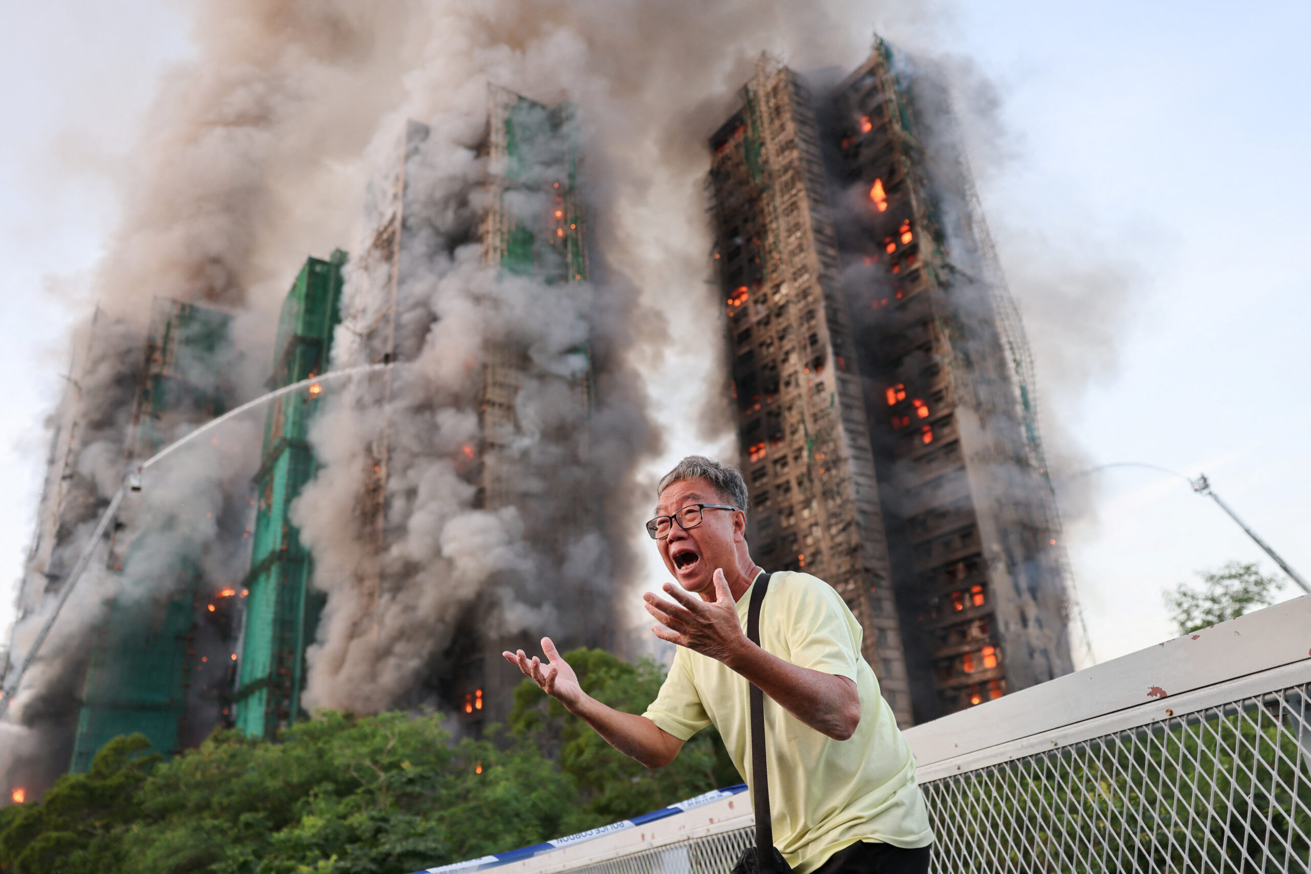 A man reacts as flames engulf multiple buildings at Wang Fuk Court housing estate.