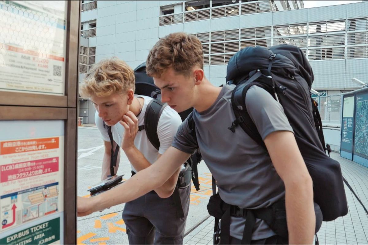 Alfie and Owen study a map, in t-shirts and backpacks 