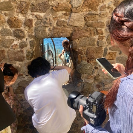 Tourists crowd around the Forat del Dimoni in Tossa de Mar’s old city wall to take photos.