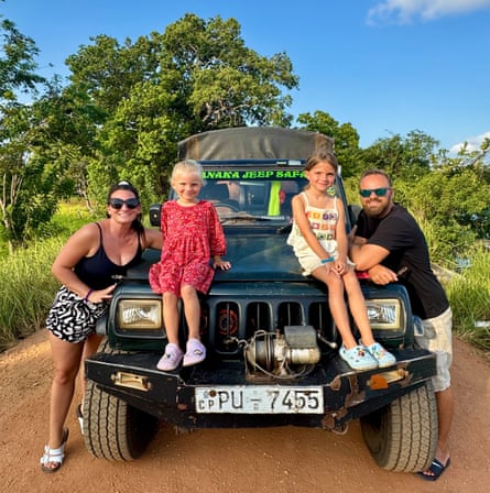 A woman and man leaning on the bonnet of a jeep in Sri Lanka, with two children sitting between them