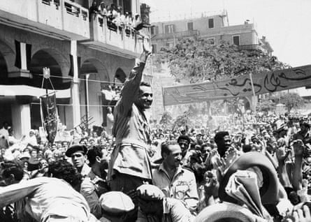 Gamal Abdel Nasser waves to the crowd as Egypt formally takes control of the Suez canal from the UK in June 1956