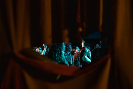 A cheering crowd viewed through a gap in curtains