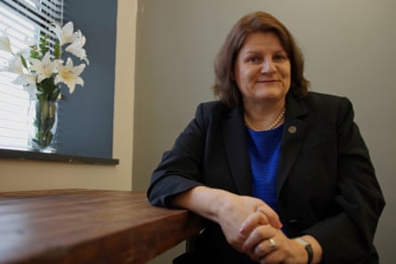 woman wearing black suit and blue shirt poses at table
