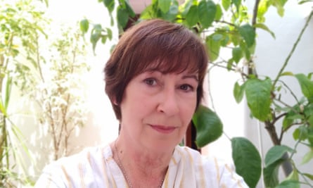 Lynda Rae, with short hair, in front of plants, smiling very slightly