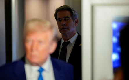 A man stands in the shadows behind Donald Trump