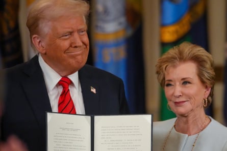 A woman and a man smile side by side as they pose with a document