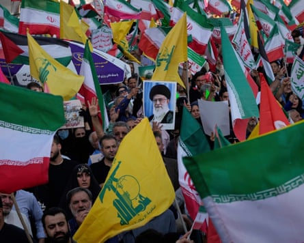 Dozens of Iranian and Hezbollah flags held aloft by a crowd, along with a photo of the then ayatollah, Ali Khamenei