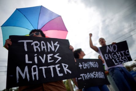 people hold black signs with white writing that says ‘trans lives matter’