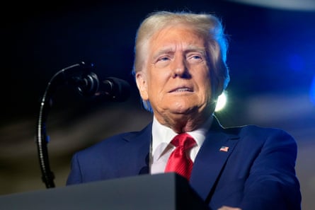 man wearing navy suit stands behind microphone