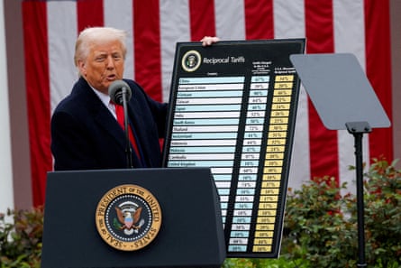 Donald Trump speaks at a lectern outside as he holds a chart outlining new tariffs