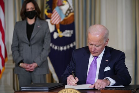 a women wearing a face mask watches a man signing a document