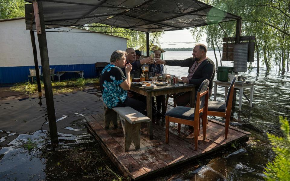Lyudmila Kulachok, 54, left, with her family having dinner at the flooded courtyard of their house in the island of Kakhovka reservoir on Dnipro river near Lysohirka - Evgeniy Maloletka/AP