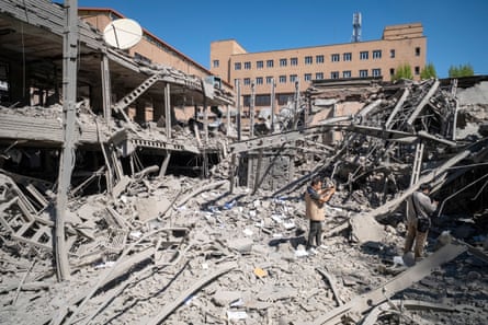A man stands amid the twisted metal ruins of a large modern building in Iran