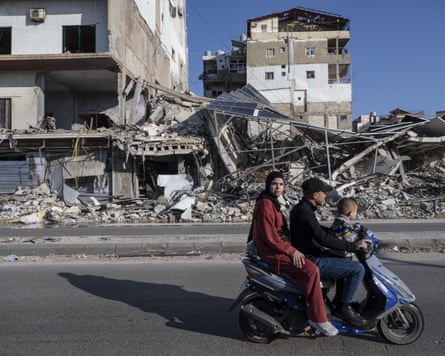 A family on a motorbike pass by the ruins of a building destroyed by an Israeli strike on Tyre, southern Lebanon.