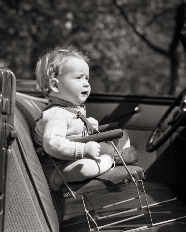 A child sitting forward in a car with thin wires and straps attaching them in a seat