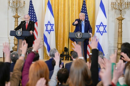 two men speaking to a crowd with their hands up