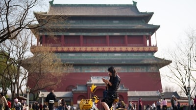 A woman looks at her phone while riding at the Drum Tower in Beijing, China, Tuesday, March 31, 2026. (AP Photo/Vincent Thian) (AP)