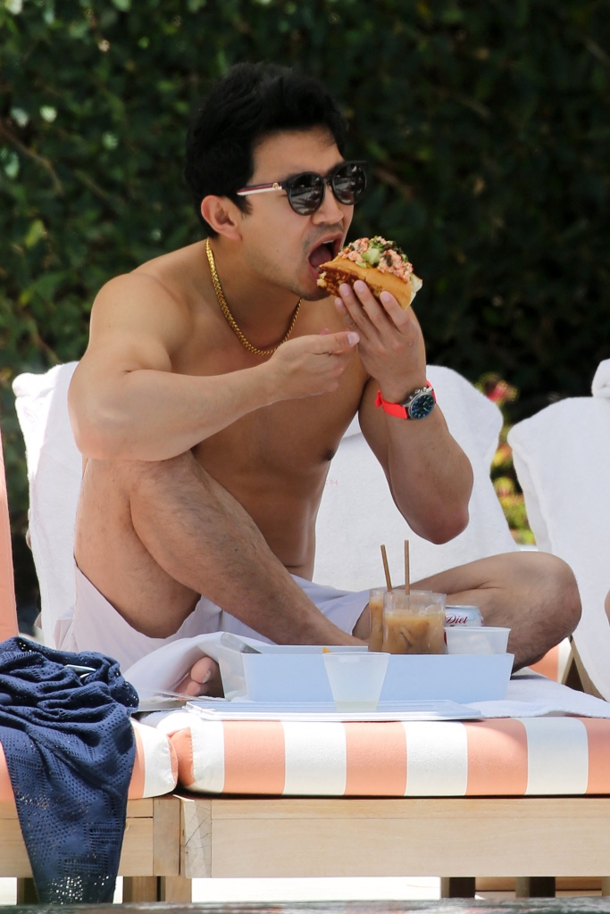 Liu tucks eats a lobster roll as he relaxes by the pool with girlfriend Allison Hsu in Miami. 