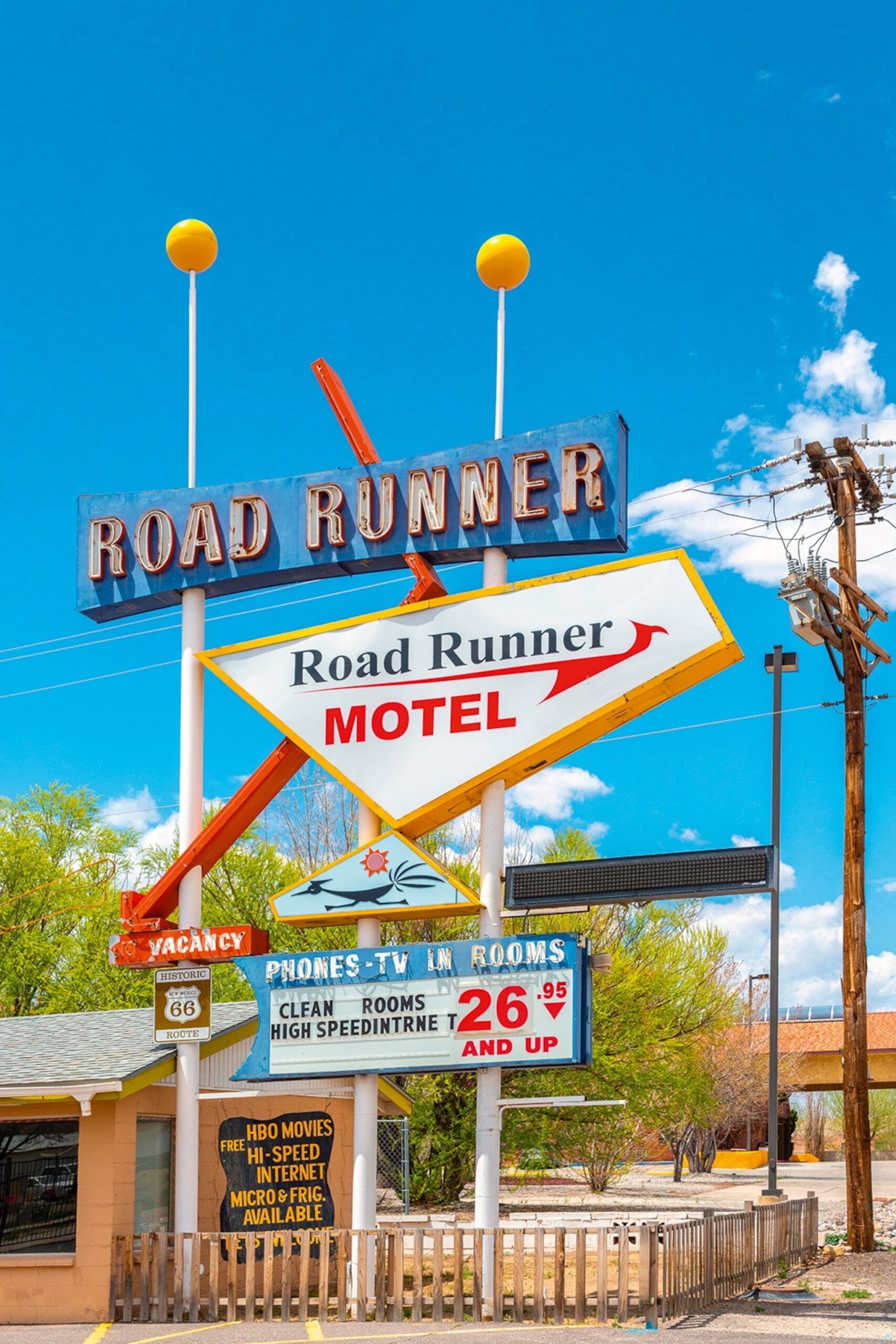 A multi-tiered sign for 'Roadrunner' Motel on Route 66 on a sunny day.