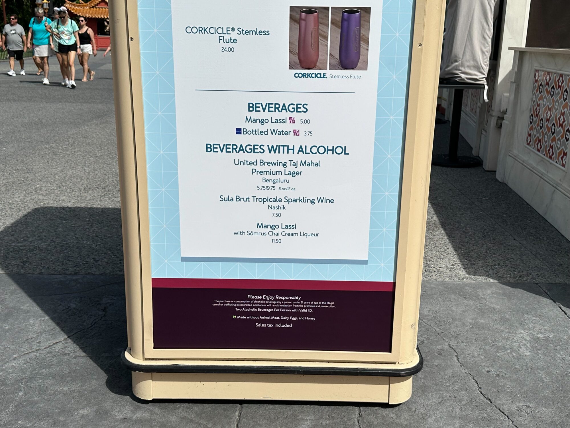 Menus (With Prices) for 2024 EPCOT International Food & Wine Festival 24 A sign at the food & wine festival lists beverages available at the stand, including mango lassi, bottled water, and various alcoholic drinks such as beer, sparkling wine, and mango lassi with Somrus Chai Cream Liqueur.
