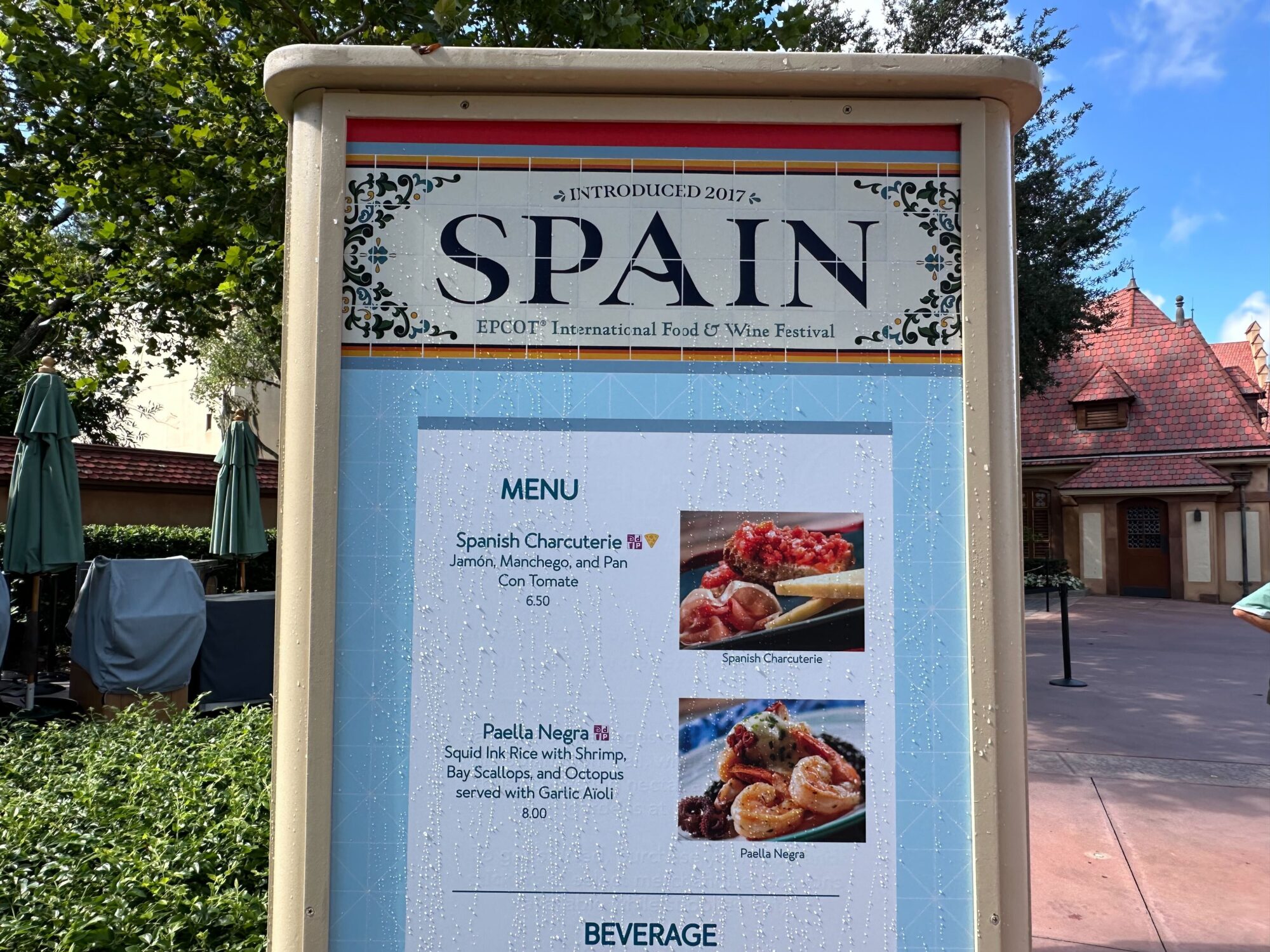 Menus (With Prices) for 2024 EPCOT International Food & Wine Festival 35 A sign at the EPCOT International Food & Wine Festival displays the Spain booth's menu, featuring Spanish Charcuterie and Paella Negra, under a header introduced in 2017.