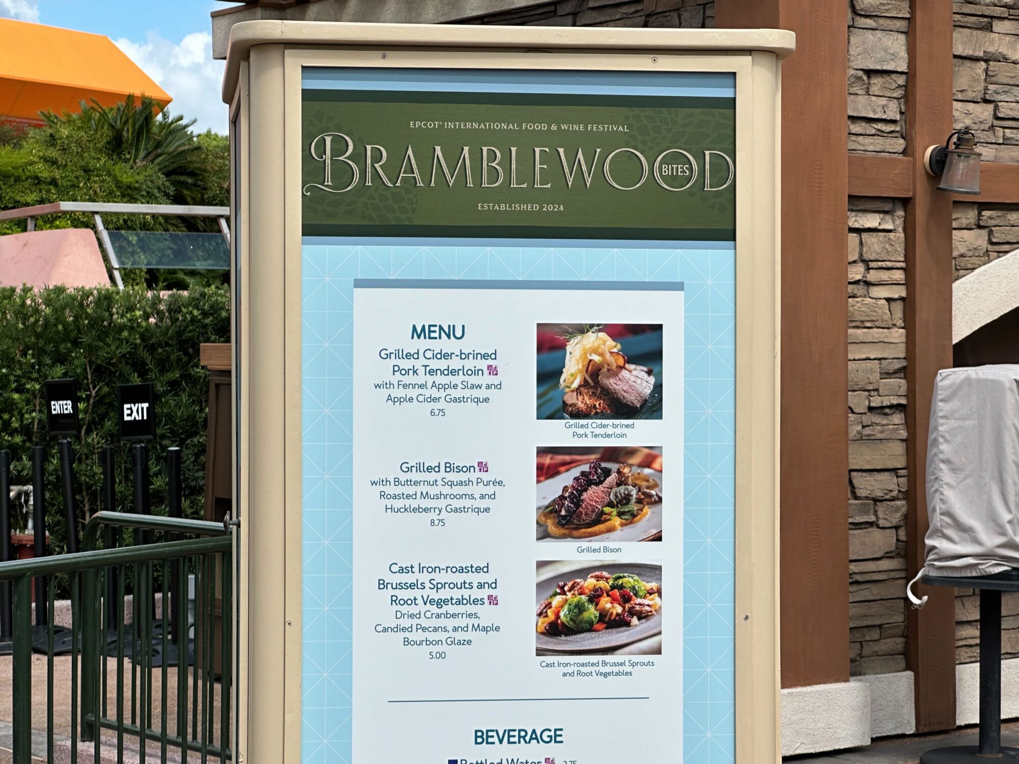 Menus (With Prices) for 2024 EPCOT International Food & Wine Festival 71 Outdoor restaurant menu board for Bramblewood Bites, featuring dishes such as Grilled Cider-brined Pork Tenderloin, Grilled Bison, and Cast Iron-roasted Brussels Sprouts and Root Vegetables, perfect for a food & wine festival.
