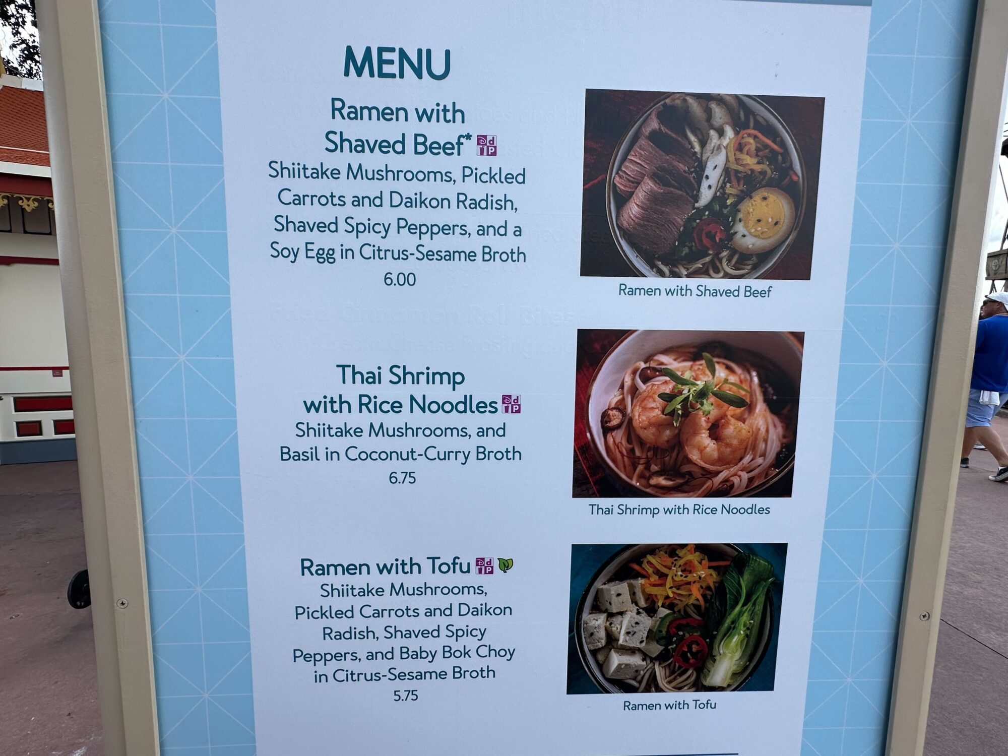 Menus (With Prices) for 2024 EPCOT International Food & Wine Festival 17 Close-up of a menu board at the food & wine festival, showcasing three ramen dishes: Ramen with Shaved Beef, Thai Shrimp with Rice Noodles, and Ramen with Tofu. Prices and descriptions are provided for each dish.