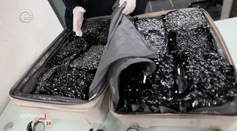 Suitcase filled with dark, crystalline substance.