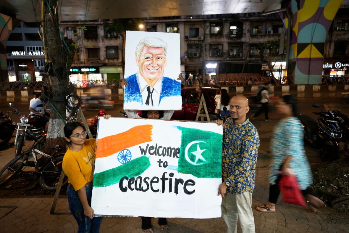 People hold up a signs depicting flags, a person's portrait and the words, 'Welcome to ceasefire.'