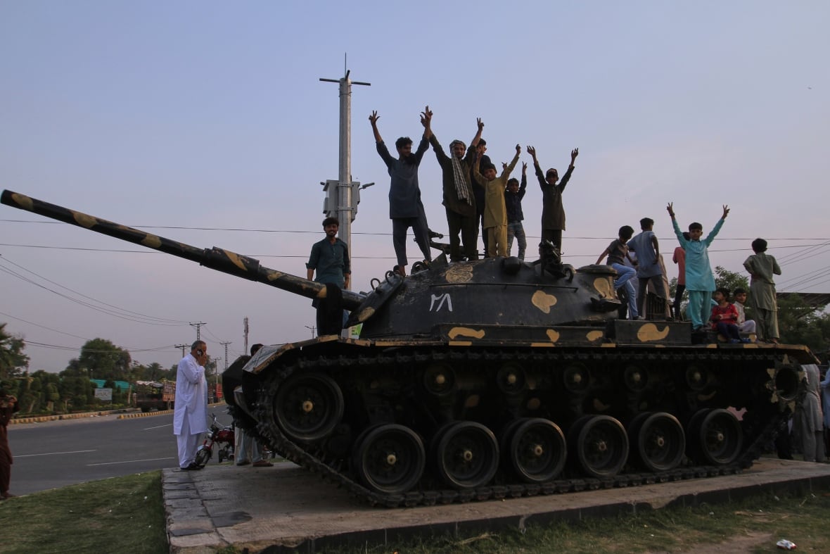 People cheer and celebrate atop a tank.