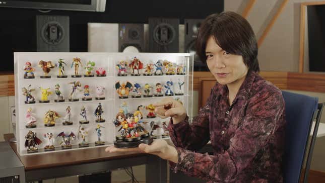 Masahiro Sakurai holds up amiibo figures.