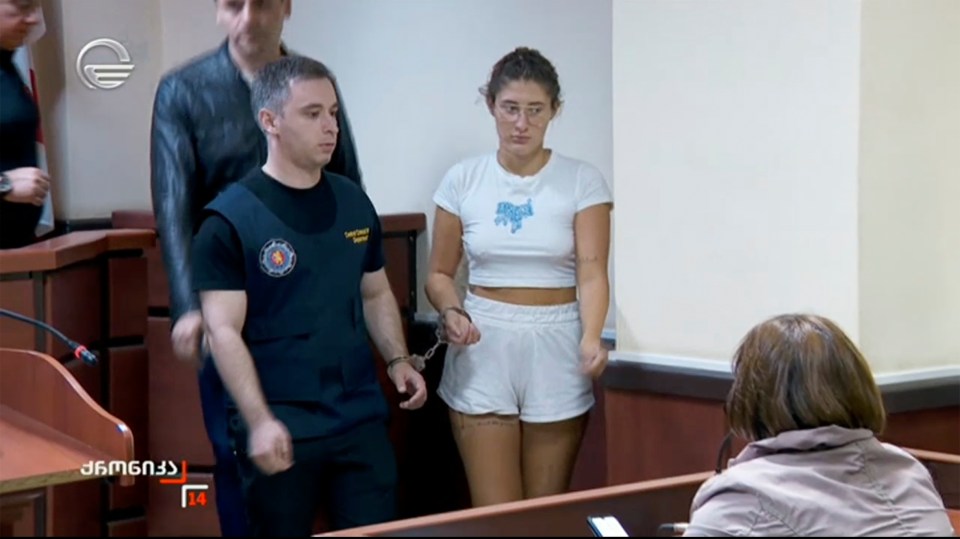 A handcuffed young woman in court.