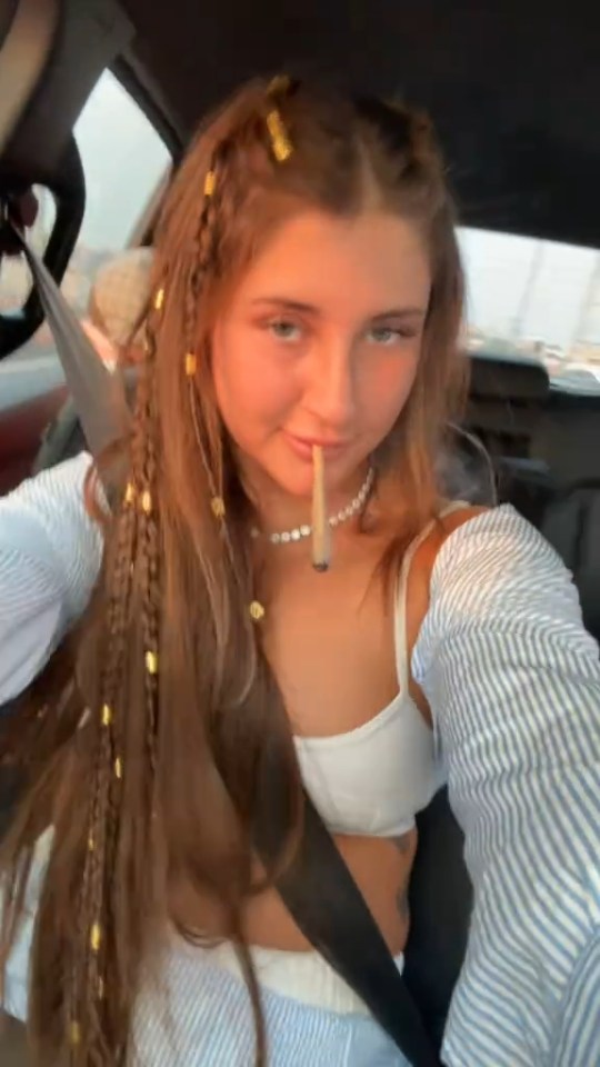 Teenage girl in a car holding a joint.