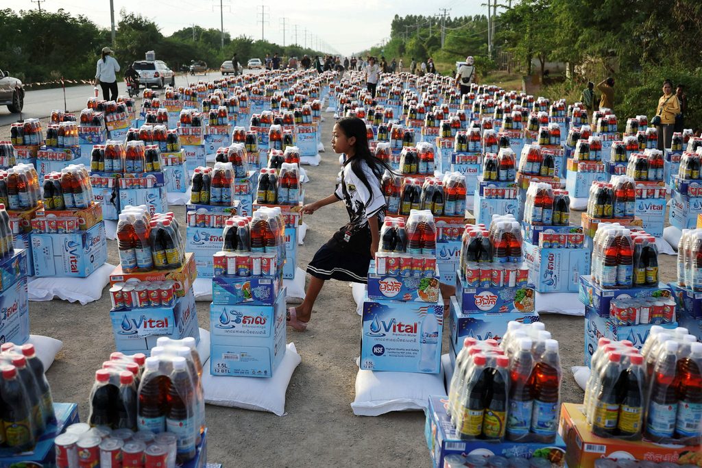 A girl runs between supplies at Wat Por Sovannaram refugee camp, amid clashes between Thailand and Cambodia along a disputed border area, in Ou Chrov district