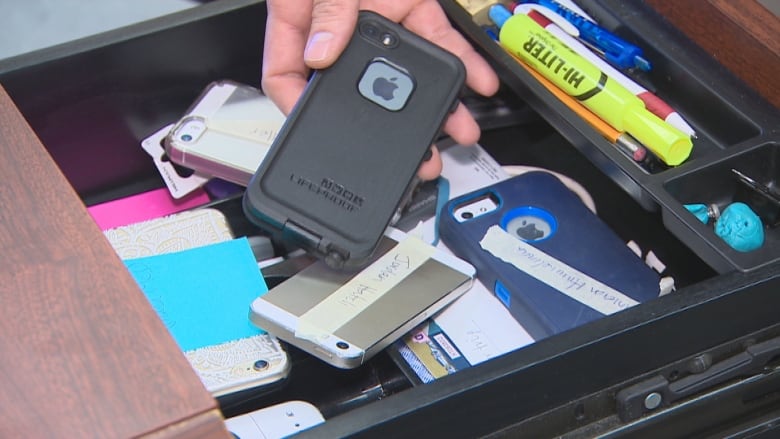 Hands place cellphones in a drawer