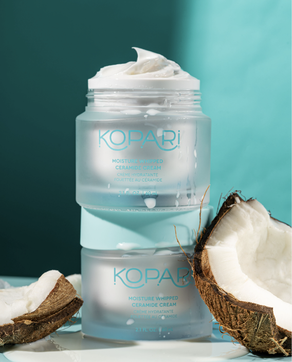 Kopari Moisture Whipped Ceramide Cream stacked on top of another, with coconut husks by the side.