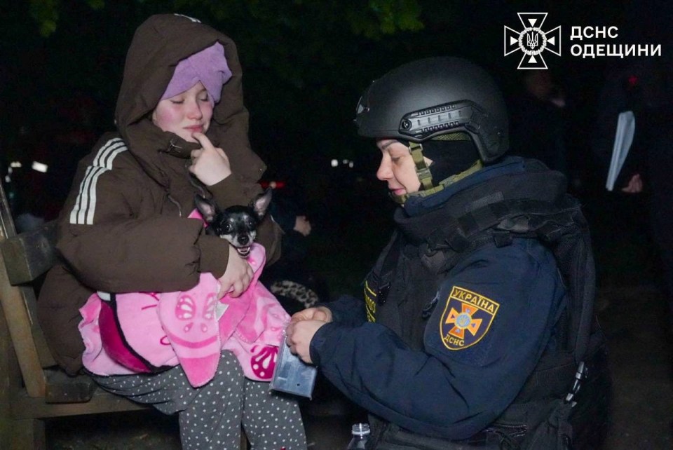 Emergency psychologist comforting a child with a small dog after a drone strike in Odesa, Ukraine.