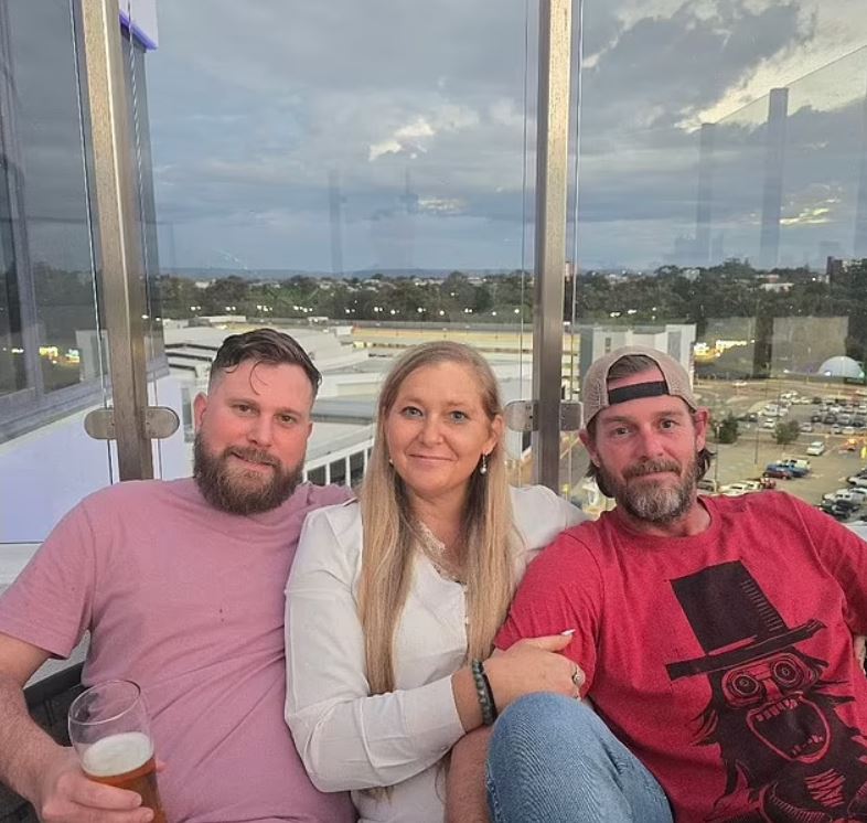 Three people sitting together outdoors.